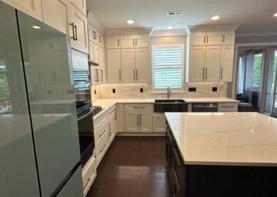 Contemporary kitchen with updated appliances, navy blue island with quartz countertops, white shaker cabinets, subway tile backsplash, and a farmhouse sink.