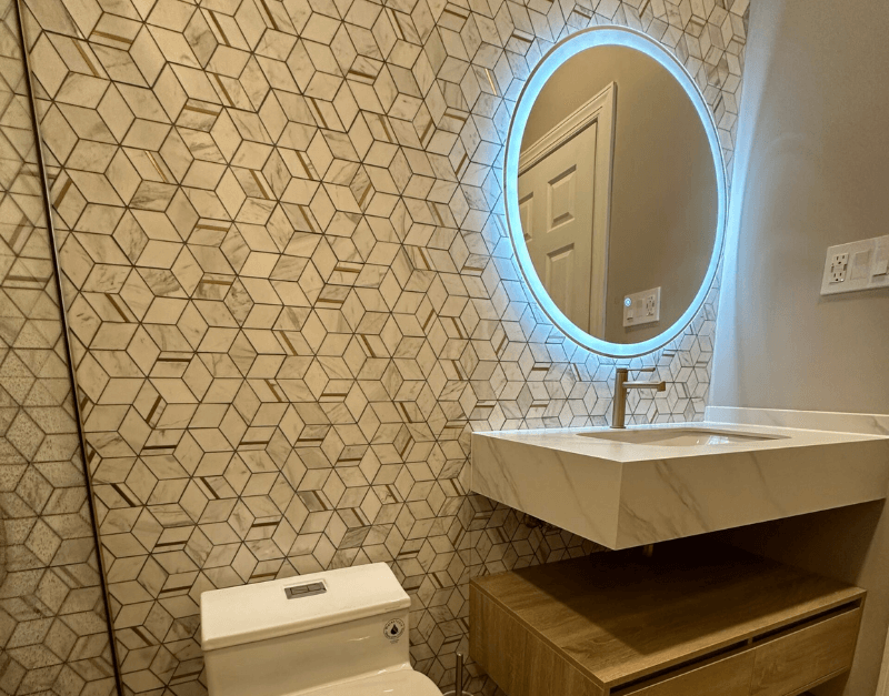 Modern Bathroom with Smart Features Bathroom with a floating sink, illuminated circular mirror, and geometric wall tiles for a modern and stylish design.