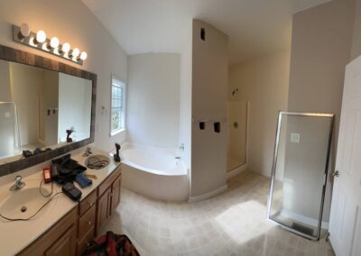 A bathroom in the starting phase of a remodel, prepared for a modern upgrade with a new double-sink vanity, updated walk-in shower, redesigned bathtub area, and planned improvements to lighting, flooring, and fixtures.