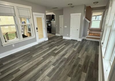 A room with new luxury vinyl plank flooring in a gray tone, complemented by neutral wall paint, clean trim, and natural lighting, creating a modern and inviting space.