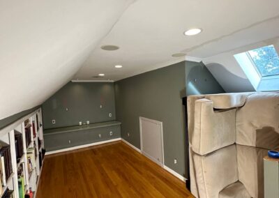 A room with newly refinished hardwood floors, freshly painted gray walls, updated trim, and recessed lighting, creating a modern and clean atmosphere.