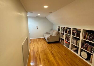A room with newly refinished hardwood flooring, recessed ceiling lights, and built-in bookshelves, providing a polished and spacious look.