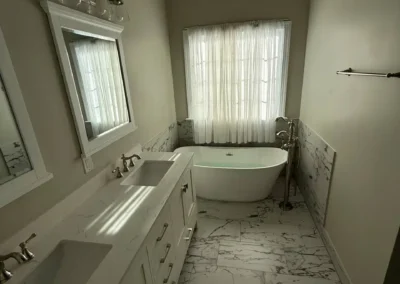Luxury bathroom with double vanity, marble floor, and freestanding tub.