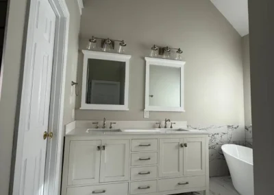 Bathroom with white double vanity, freestanding tub, and marble flooring.