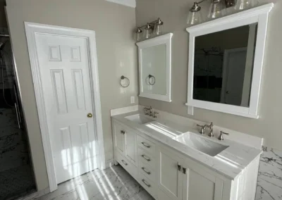 Bathroom with white double vanity, marble floor, and framed mirrors.