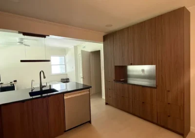 Modern kitchen with wood cabinetry, black countertops, and stainless steel accents.