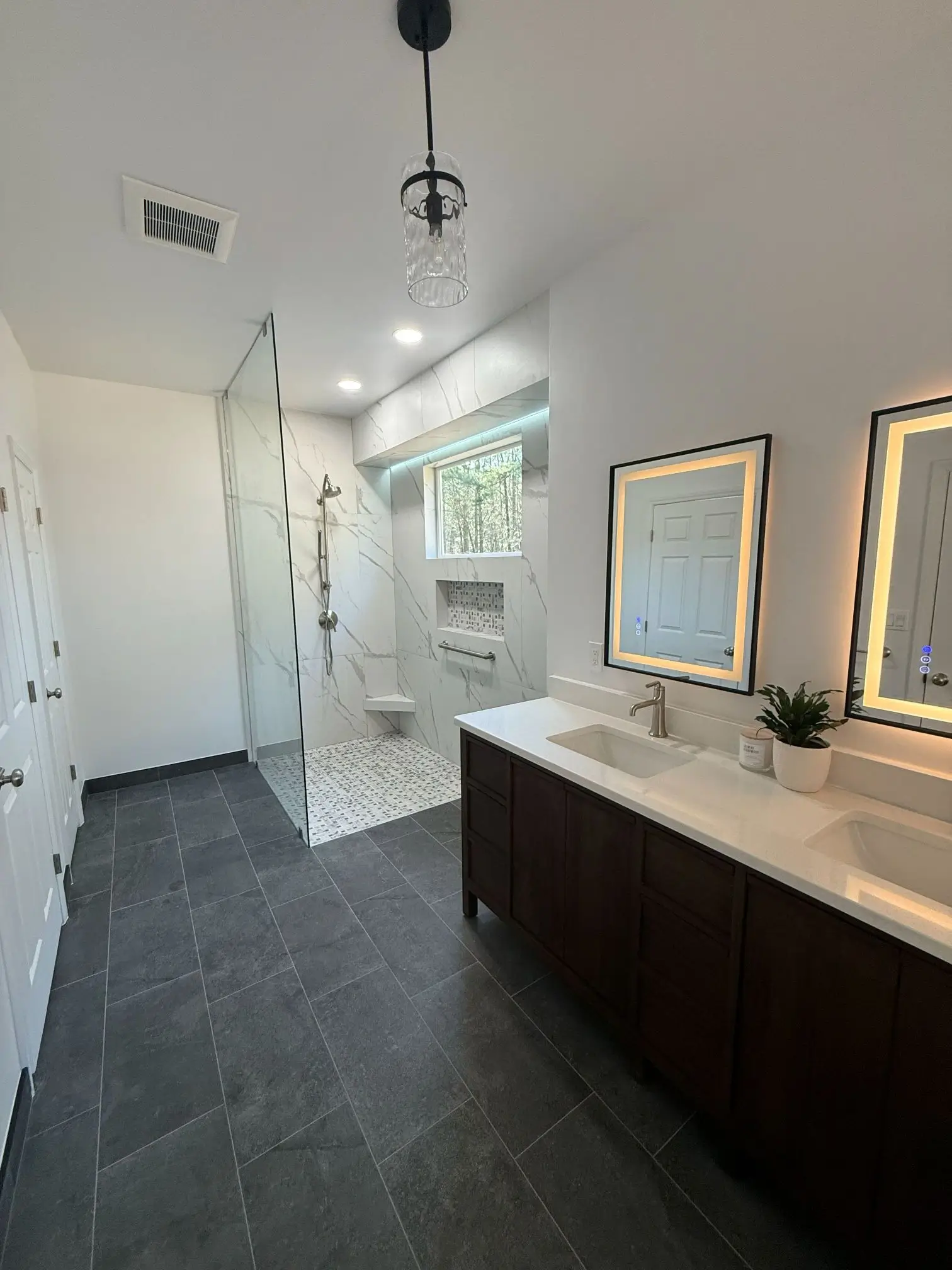Contemporary bathroom remodel with dark tile flooring and double vanity