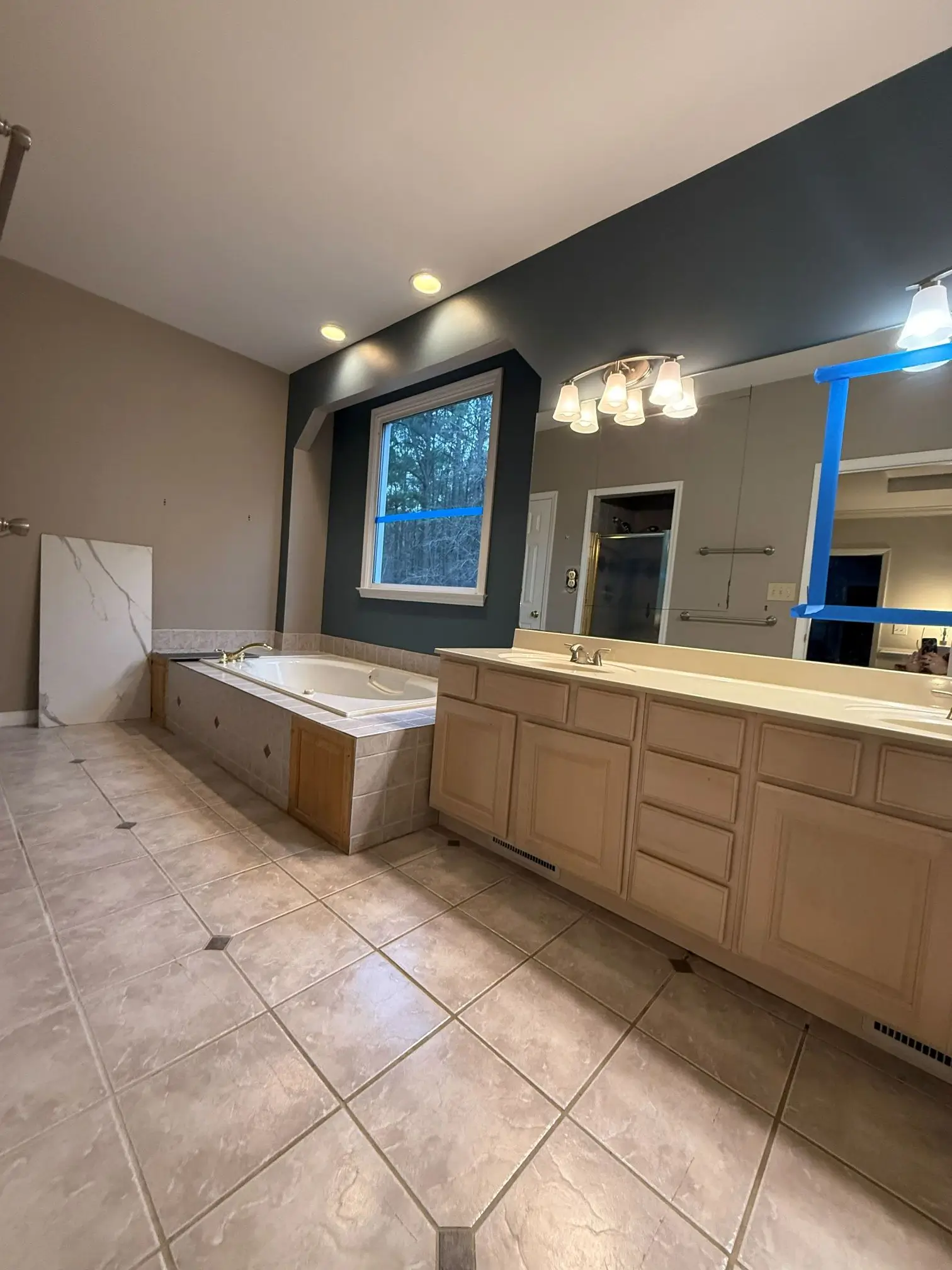Large outdated bathroom before renovation with old bathtub and vanity