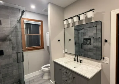 Small bathroom remodel with black tile shower and custom vanity