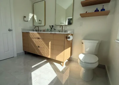 Bright modern bathroom renovation with wooden vanity and open shelving