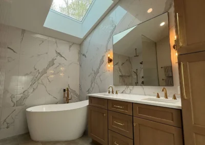 Spacious bathroom remodel with skylight, bathtub and marble walls